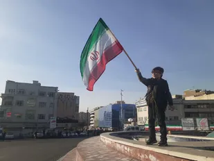 اهتزار پرچم ایران به دست یک نوجوان در میدان انقلاب